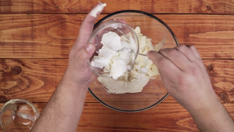 adding ingredients to the bowl to prepare the cake