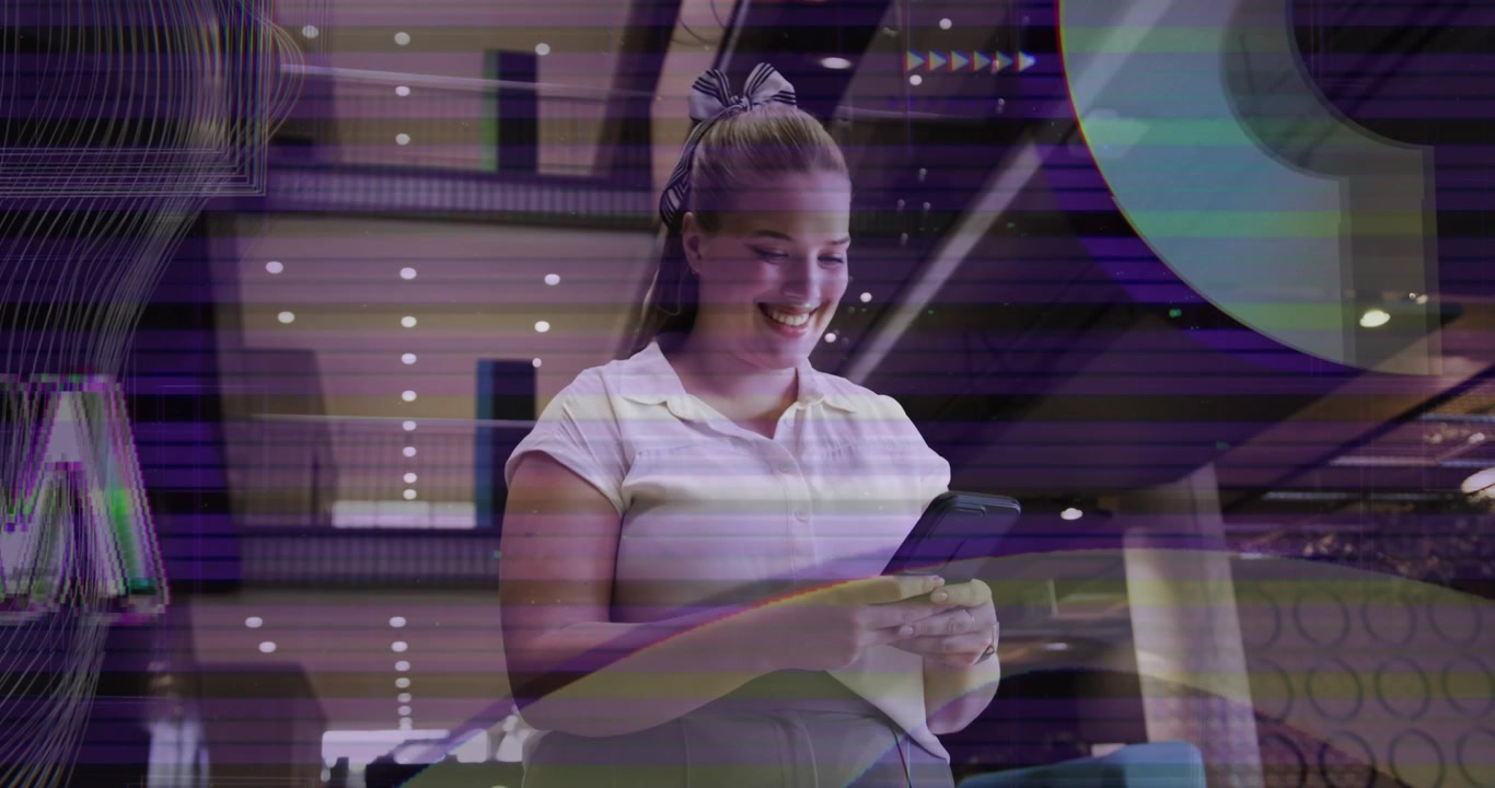 Mujer tocando la pantalla del teléfono en el vestíbulo corporativo, generando formas de colores y sonriendo ante contenido divertido.