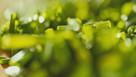 close-macro-shot-of-fresh-chopped-chives-laying-on-a-wooden-cutting-board,-rotating-camera