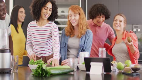 un grupo feliz de amigos diversos preparando una bebida saludable en la cocina juntos