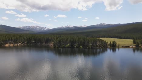 Aerial-view-of-the-shore-of-Park-Reservoir-with-Clouds-Peak-Wilderness-in-the-background-in-Bighorn-National-Forest-in-Wyoming-on-a-summer-day