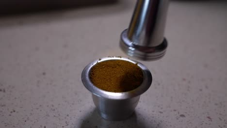 primer plano de inox tamper presionando café en polvo en cápsula de café reutilizable en cámara lenta
