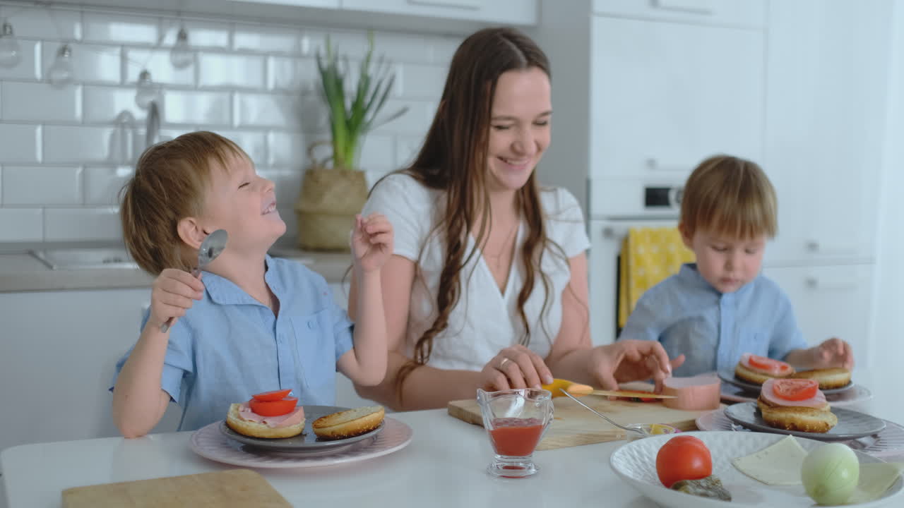 mamá con dos hijos en la cocina en la mesa preparando una hamburguesa para el almuerzo
