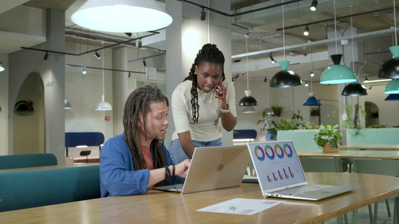 Squadra al lavoro al tavolo, donna appoggiata al telefono che indica mentre grafici animati mostrano dati aziendali