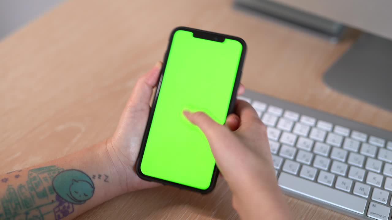 mujer tatuada con pantalla verde usando un teléfono inteligente