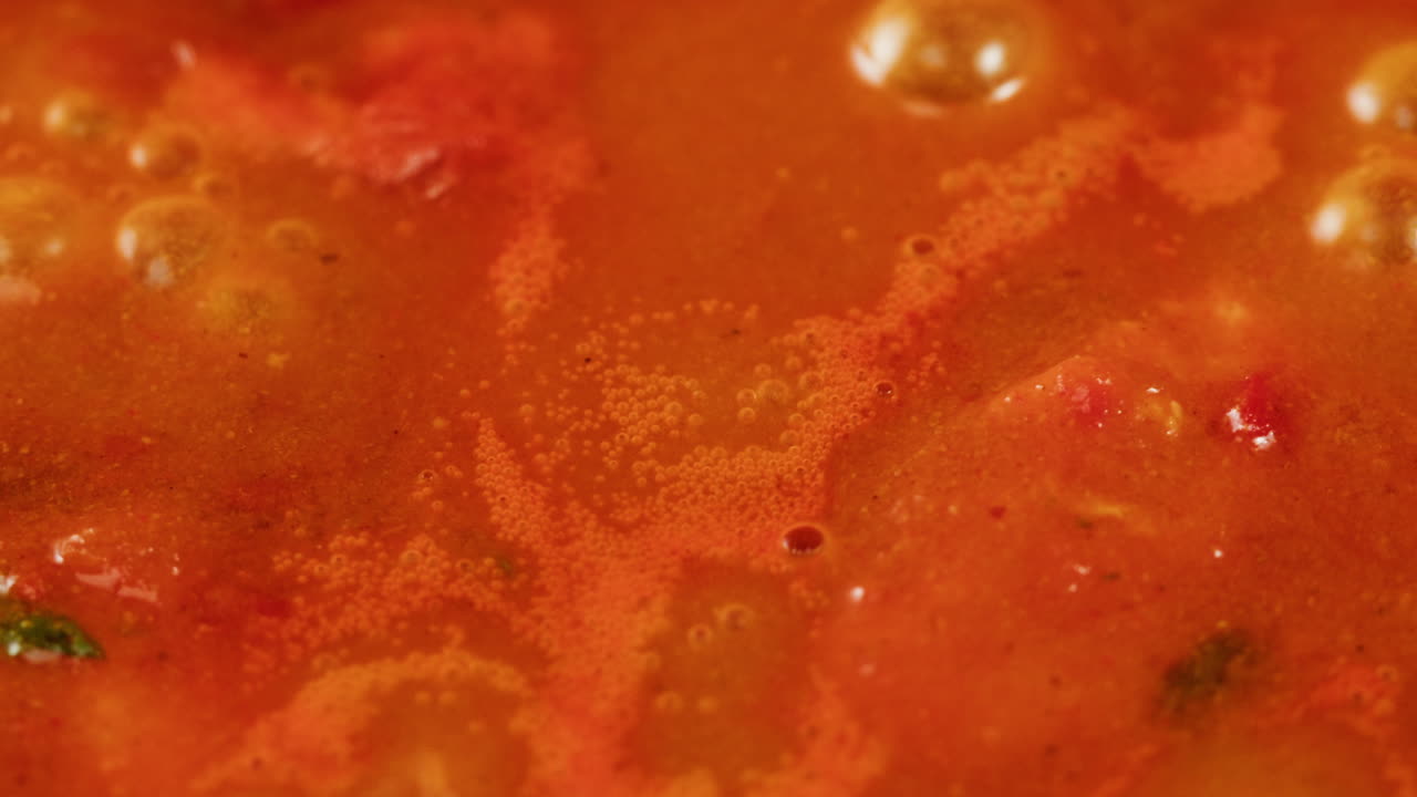 Chicken in tomato sauce is boiling on a frying pan with spices. Cooking tomato sauce curry with chicken fillet. Traditional Italian Mexican Asian dish. High quality studio shot for cafe, restaurant close up.