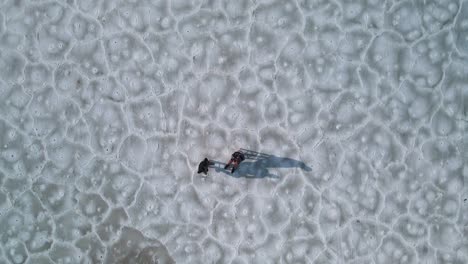 dron cinemático de arriba hacia abajo filmado en un área remota de dos personas sentadas en sillas y hablando de video aéreo 4k, salinas de bonnesville, utah, estados unidos