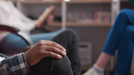 black man taps fingers on knee indoors closeup. african american guy listens to rhythmical music with friends in chill out corner. rest and relaxation