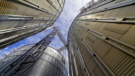 aluminum containers for storing grains. exterior of large metal elevators. close-up. view from below. camera motion around.