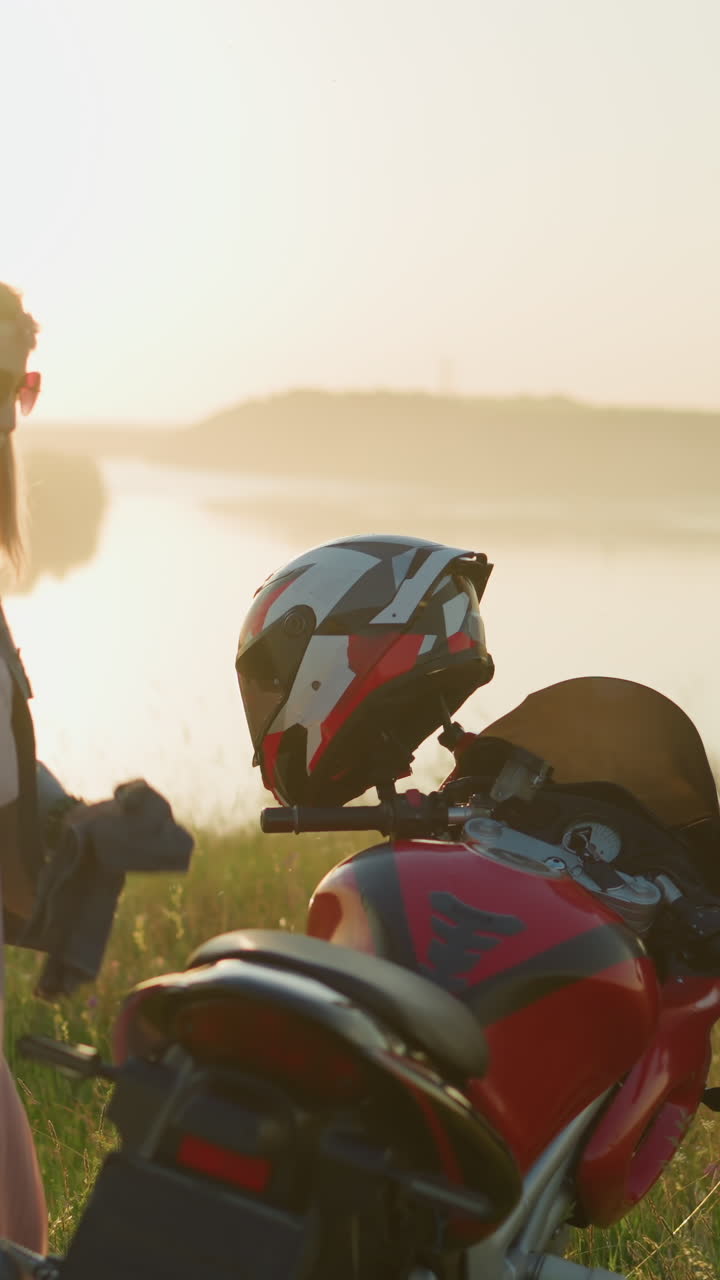 두 친구가 경치 좋은 현장에서 오토바이를 청소하는 동안 즐거움을 즐기고 있습니다. 하나는 자전거의 뒷좌석을 고 다른 하나는 해가 지는 동안 행복하게 춤을 추고 있습니다.