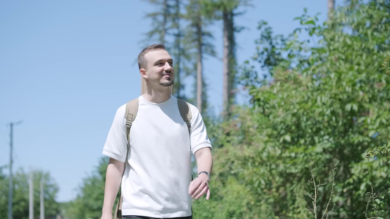 숲 근처의 거리에서 기타를 들고 는 젊은 남자