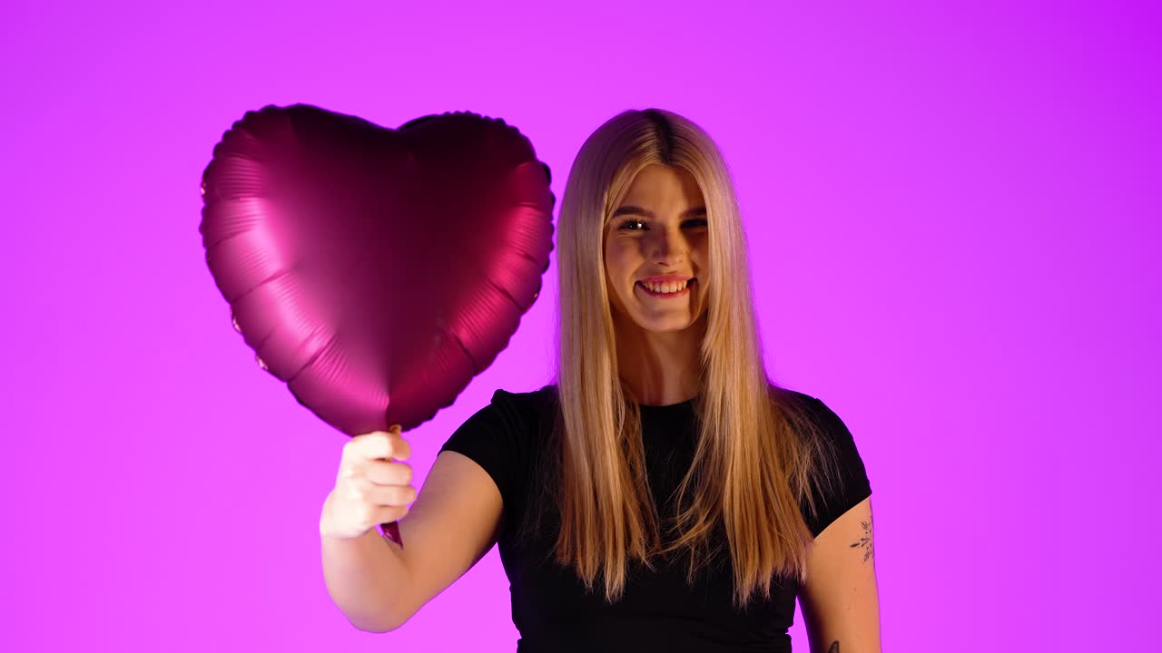 concepto día de san valentín, joven sostiene corazón rojo globo corazón en la cámara