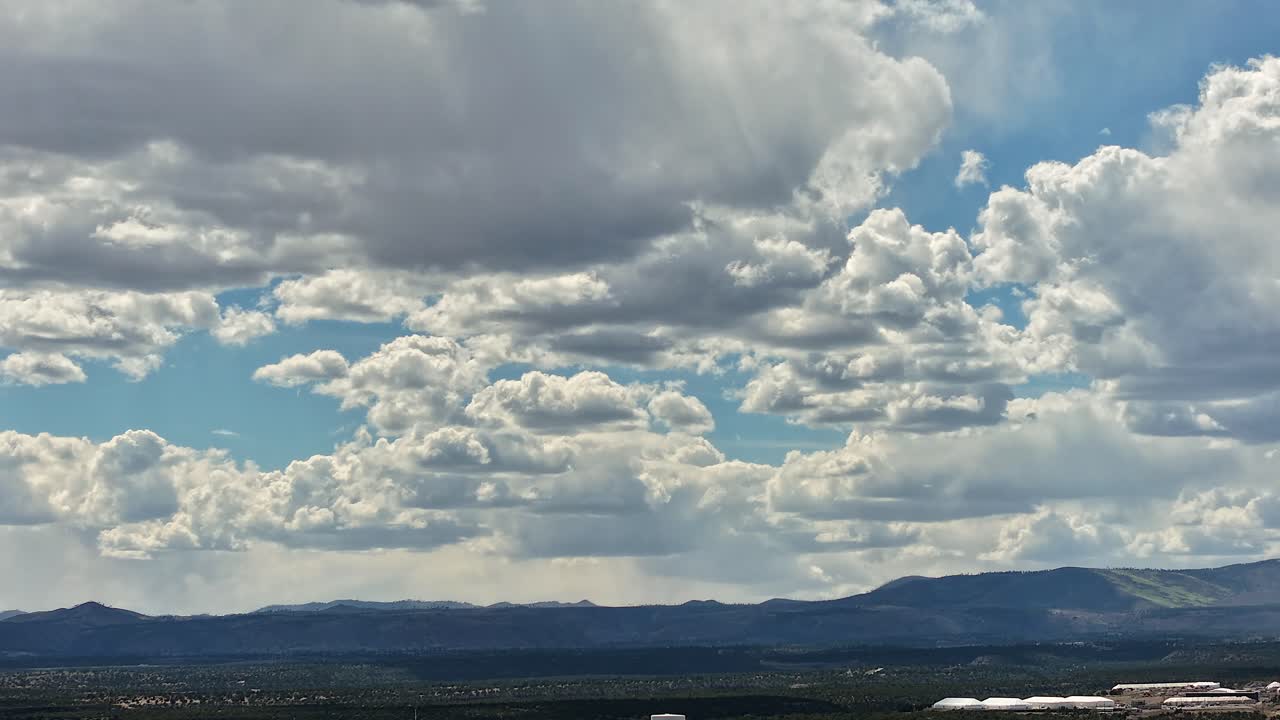 A cinematic drone hyperlapse captures a dramatic picturesque southwest landscape. Rapidly shifting clouds over rugged desert vistas create a stunning nature backdrop