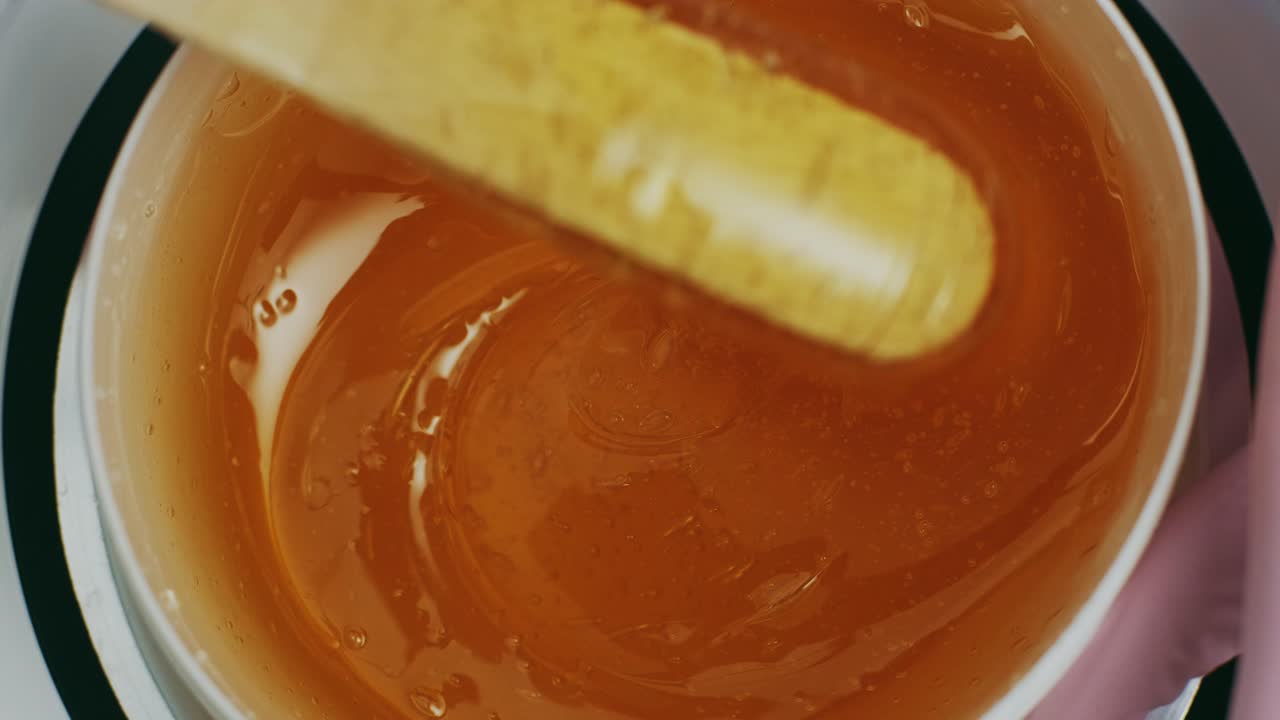Liquid sugar for skin epilation. Close up shot. depilation and beauty concept - sugar paste or wax honey for hair removing with wooden waxing spatula sticks