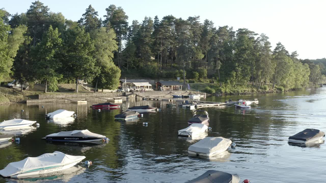 Aerial view of numerous small boats moored on calm lake by forested shore, recreational area, Marcillac La Croisille, France