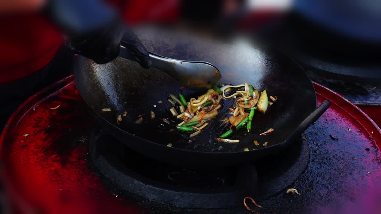 Asiatische Küche. Kochen in einer Wokpfanne. Zeitlupe