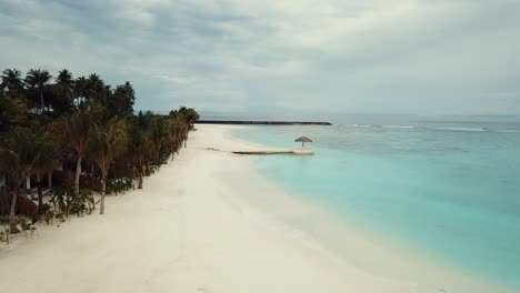 Drone-video-of-a-tropical-resort-in-the-Maldives,-blue-lagoon,-green-palms,-turquoise-shallow-water,-island-4K