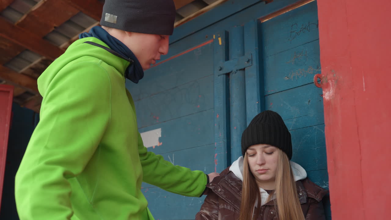긴장된 상호 작용이 있는 겨울 도시 풍경. 젊은 여성이 어깨를 터치당하면서 긴장감이 고조됩니다. 두 사람 간의 감정적, 신체적 접촉을 보여주는 도시의 겨울 풍경입니다.