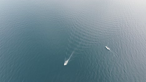 two boats on a blue lake turning around each other on the quiet water surface