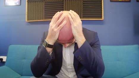 Depressed-Man-Sitting-On-Sofa-with-head-in-hands