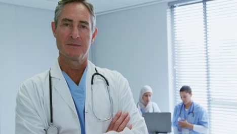 close-up of caucasian male doctor standing with arms crossed in hospital