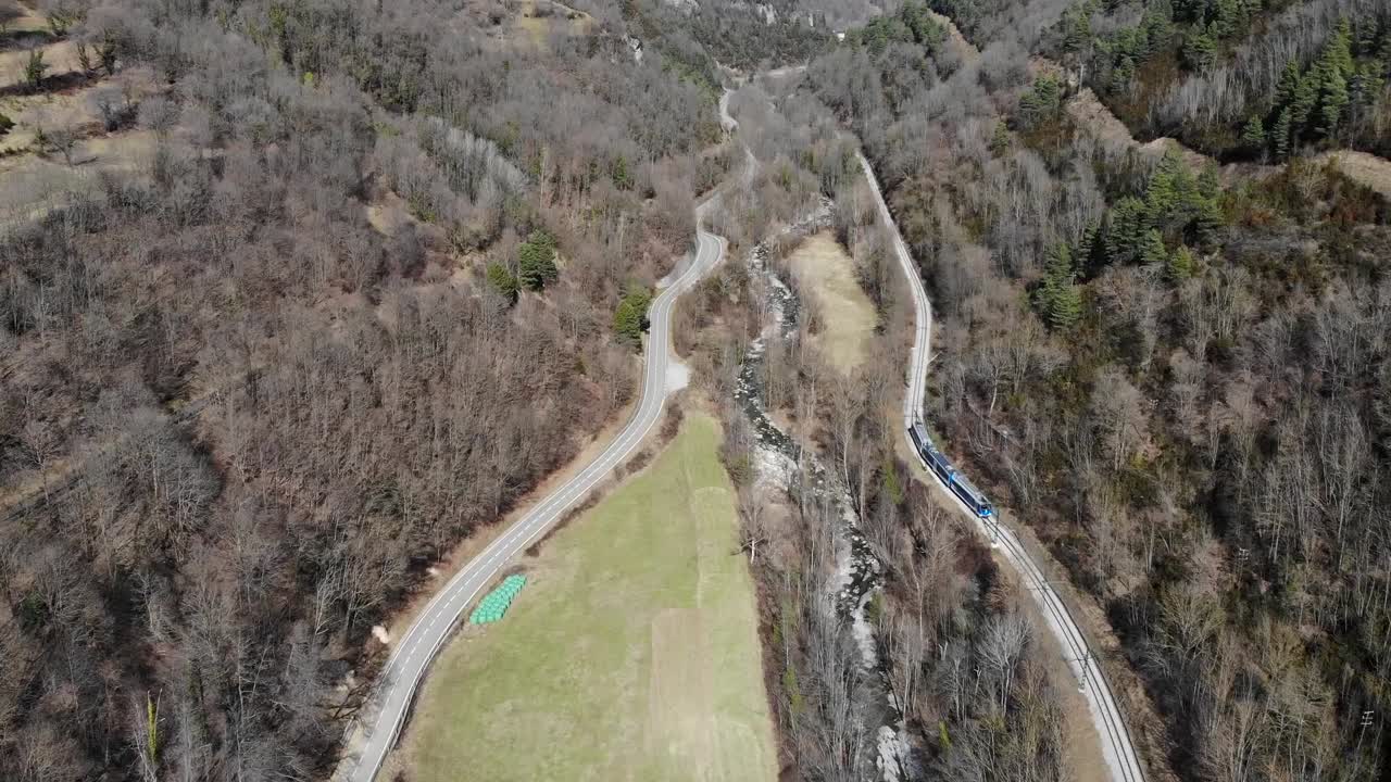 항공: 강에 가까운 계곡과 배경에 산이 있는 도로를 가로지르는 랙 레일웨이