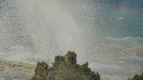 close up shot of blow hole in tinian, northern mariana island with a rainbow showing