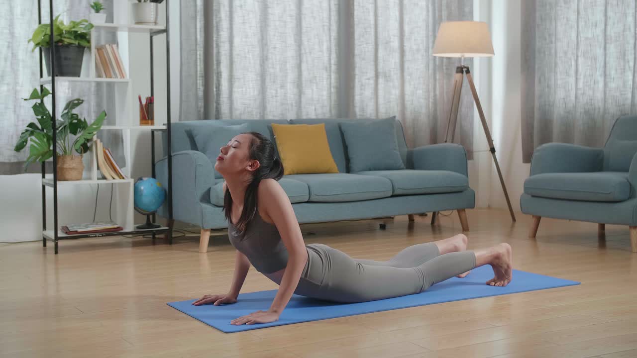 mujer haciendo postura de cobra yoga en casa