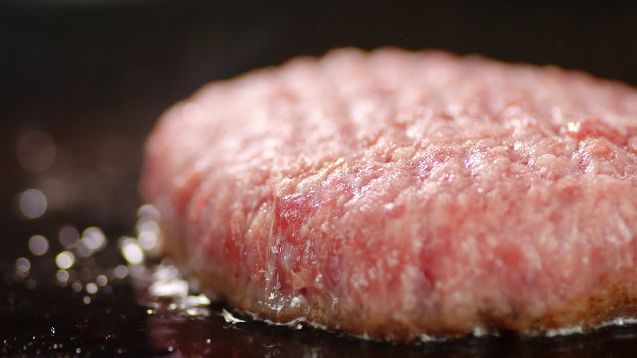 la carne cruda de la hamburguesa se fría en una sartén.