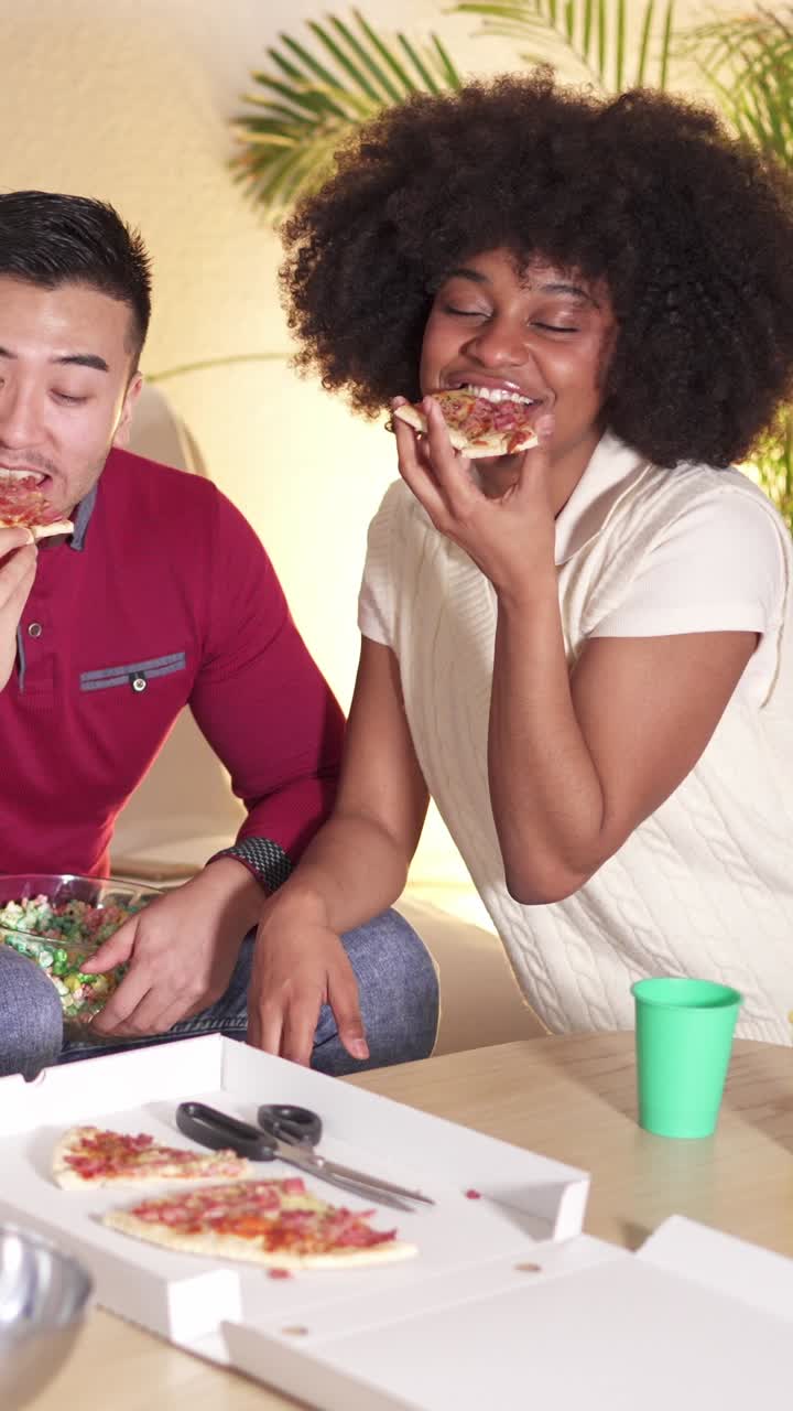 Couple or friends enjoying pizza and snacks together at home
