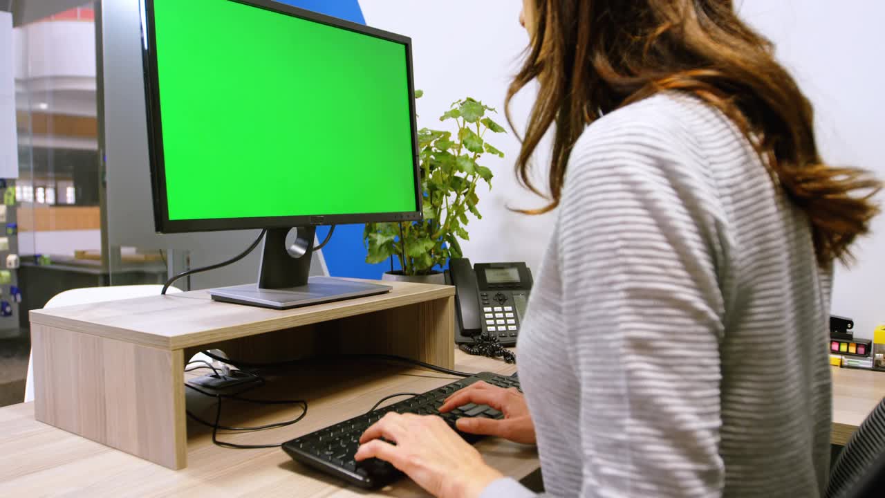 Woman typing at desk generating badges across green screen and desk showing social media engagement