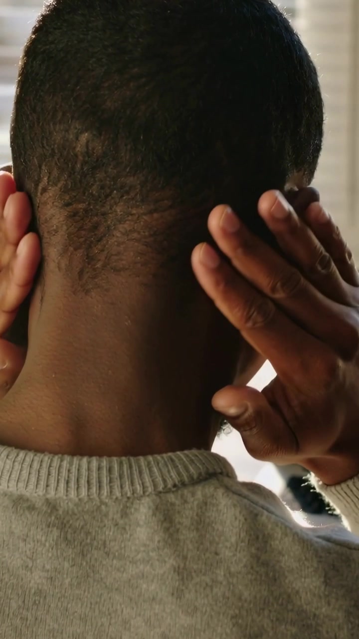 Video verticale: Uomo in maglione grigio che si massaggia il collo con le mani dopo aver digitato alla scrivania, tende a veneziana.