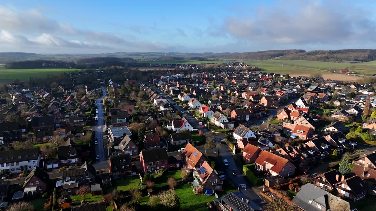 Aerial forward flight over scenic housing area of America in Autumn. Single family homes with solar Panels during sunny day. Agricultural farm fields and hills in distance. Wide shot.