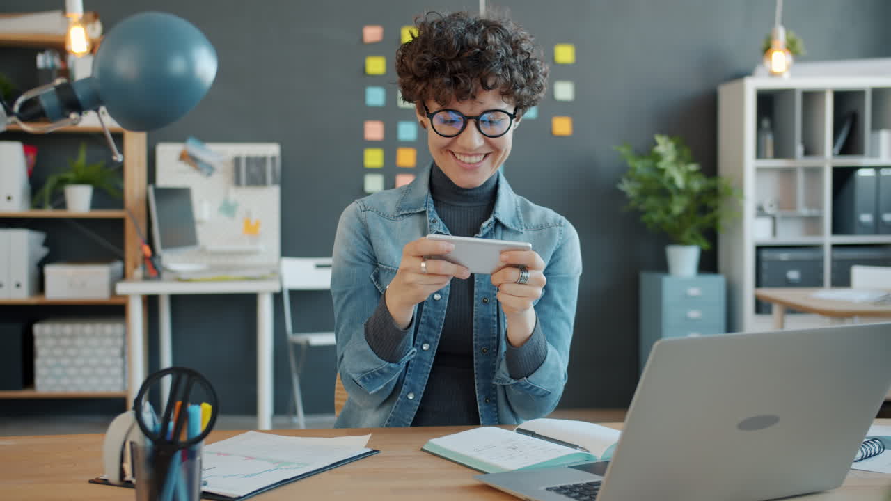 Woman Playing Game on Smartphone in Modern Office