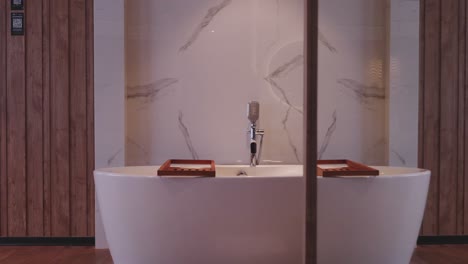 marble and wood furnishings surrounding freestanding bath in hotel room