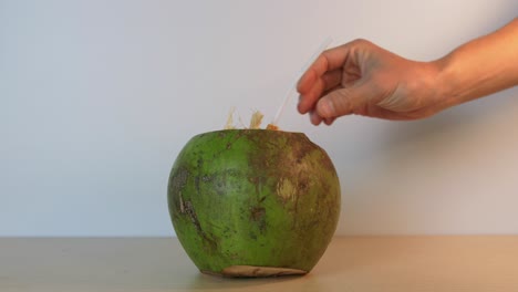 persona insertando una pajita en un delicioso coco verde en cámara lenta