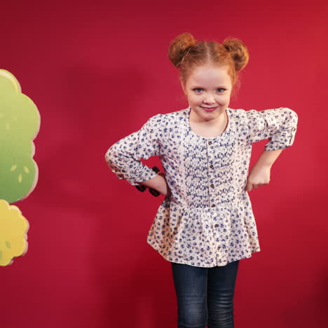 little girl with binoculars in hands posing. isolated on a red background.