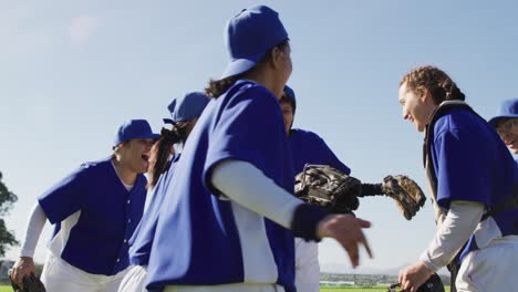 Happy-diverse-team-of-female-baseball-players-celebrating-after-game,-jumping-in-a-huddle