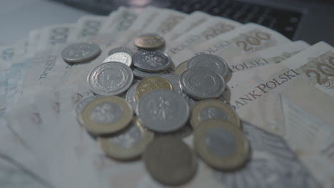 close up shot of falling polish zloty coins falling on many banknotes - cash zloty of poland