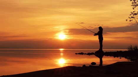 mujer pescando en una caña de pescar girando en el fondo del atardecer.
