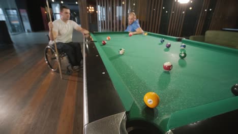 adult men with disabilities in a wheelchair play billiards in the club