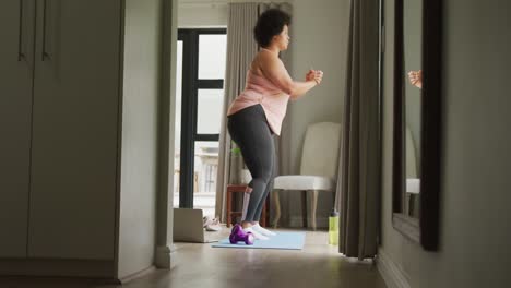 video de una mujer afroamericana de talla grande haciendo ejercicio en casa, haciendo sentadillas