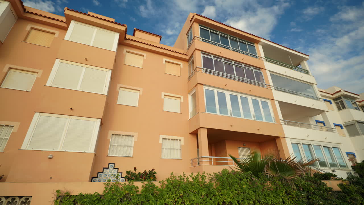 Exterior view of a residential building with balconies and windows under a blue sky