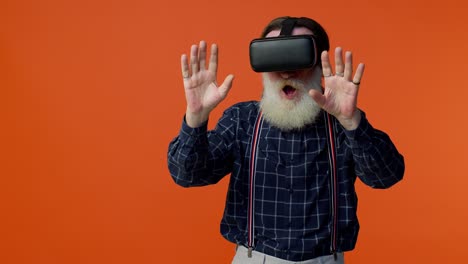 Elderly-stylish-gray-haired-man-using-headset-helmet-app-to-play-simulation-virtual-reality-VR-game