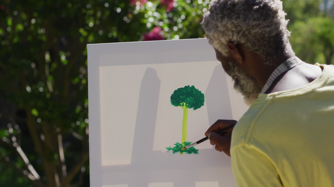 Senior african american man painting picture on a canvas in sunny garden