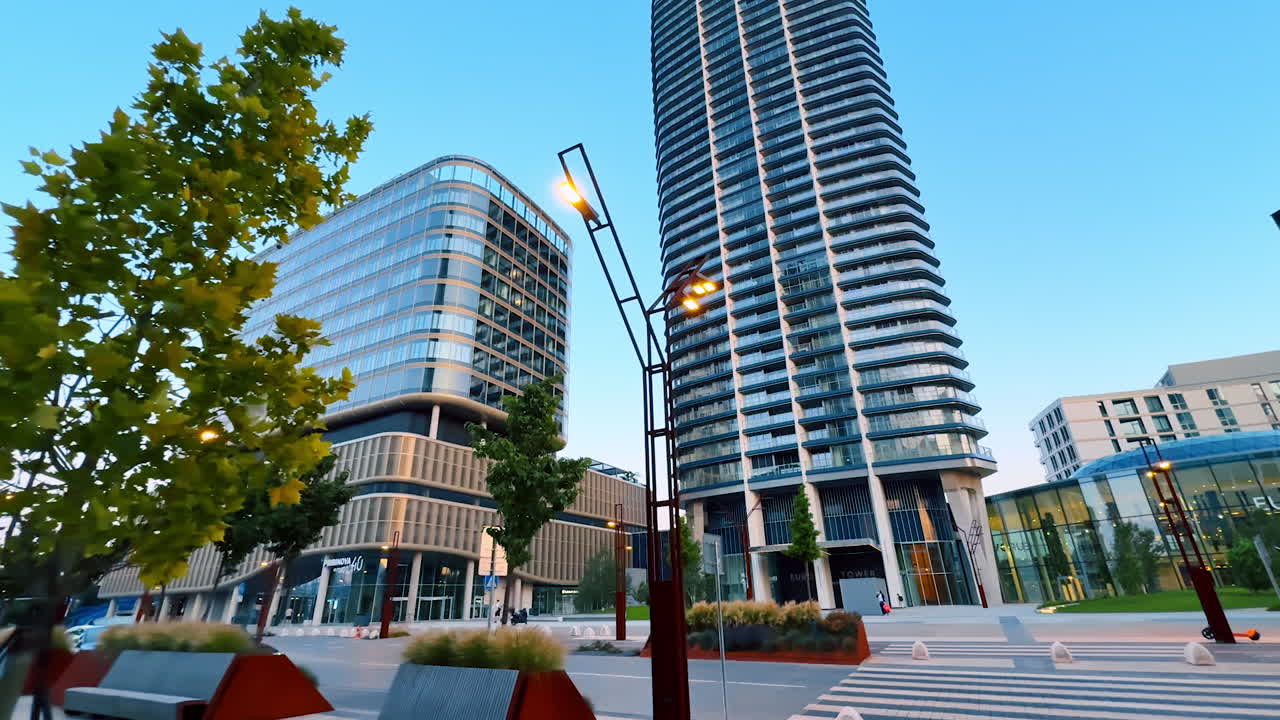 Urban plaza modern design. Tall buildings frame a vibrant plaza filled with greenery and benches, reflecting contemporary urban design at sunset