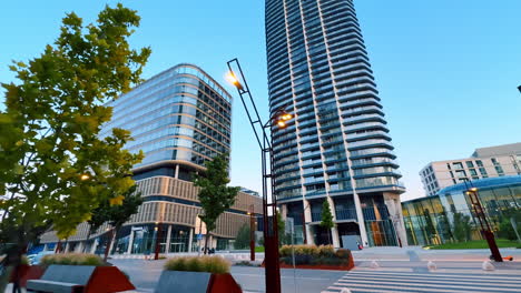 urban plaza modern design. tall buildings frame a vibrant plaza filled with greenery and benches, reflecting contemporary urban design at sunset
