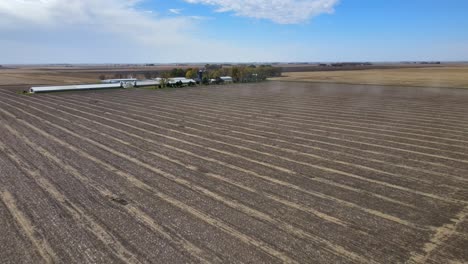 aerial drone footage of dormant fields, farm buildings and a farmhouse under blue skies in rural, midwestern iowa