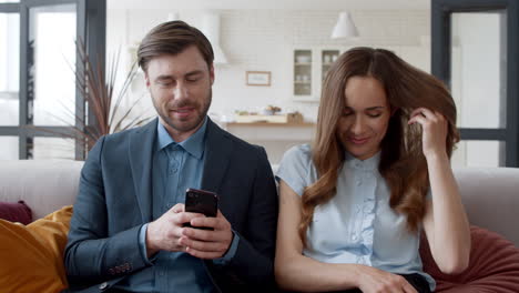 pareja de negocios sentada con el teléfono en la oficina de casa. pareja feliz divirtiéndose