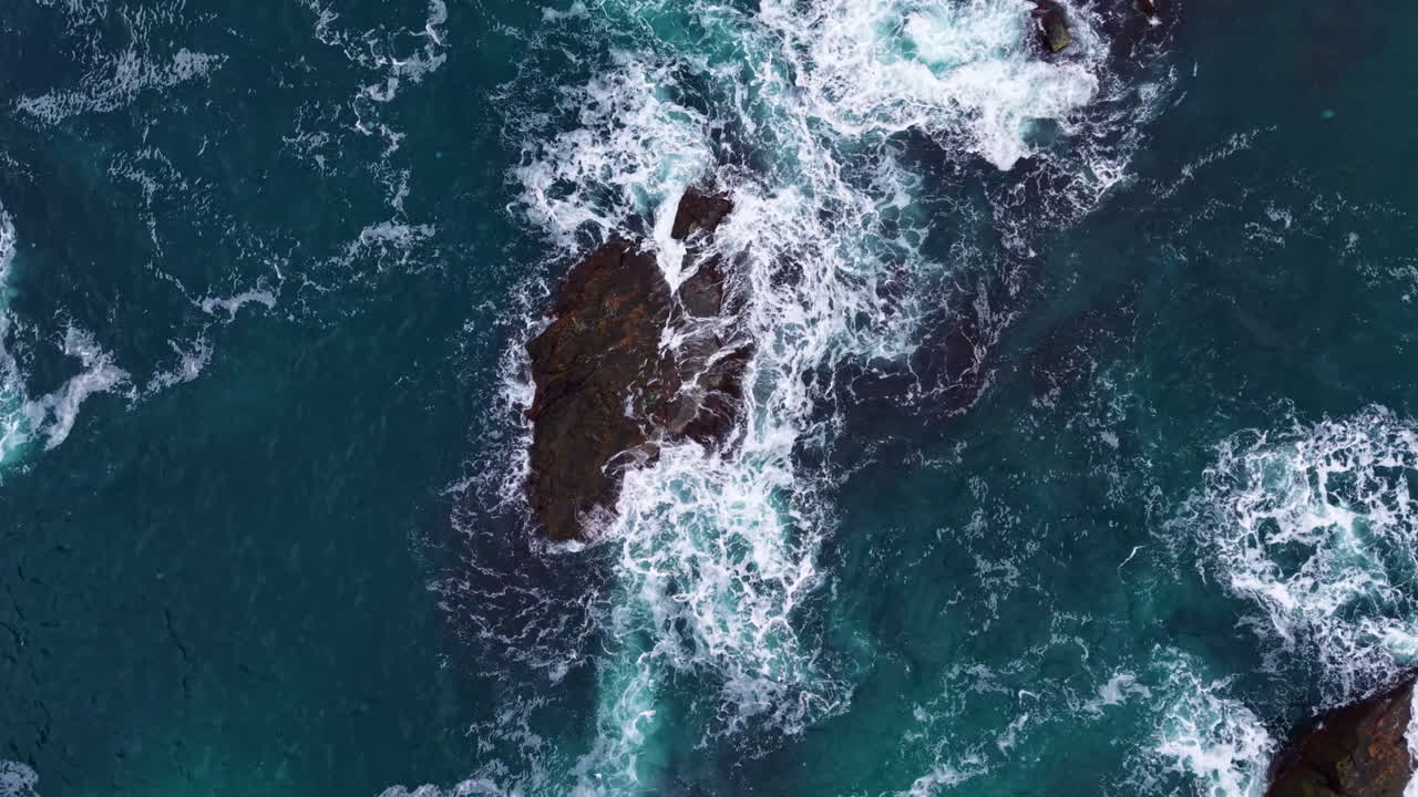 Onde che si infrangono contro rocce frastagliate in una vivace scena oceanica durante le ore diurne soleggiate